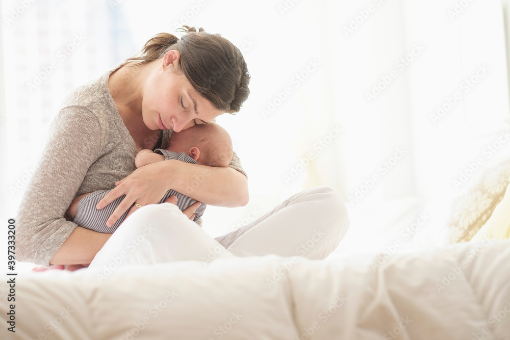 Mother embracing baby boy (2-5 months) in bed Mother embracing baby boy (2-5 months) in bed