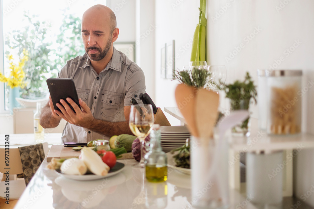 Man using digital tablet leaning on kitchen counter Man using digital tablet leaning on kitchen counter