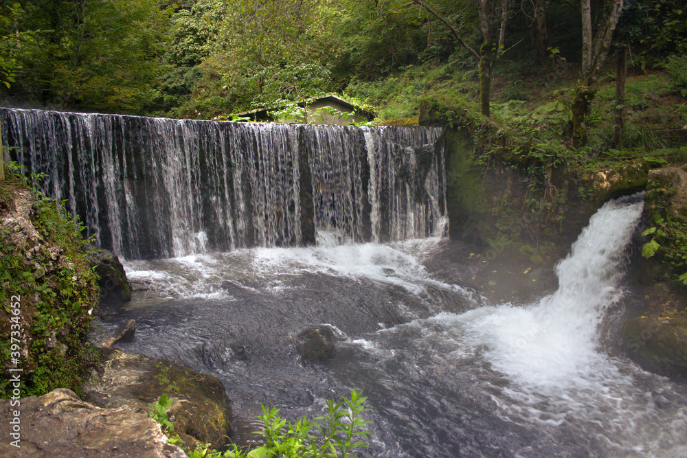 Obraz premium Beautiful nature, tourism, summer landscape, green grass and trees, river and mountains, waterfall