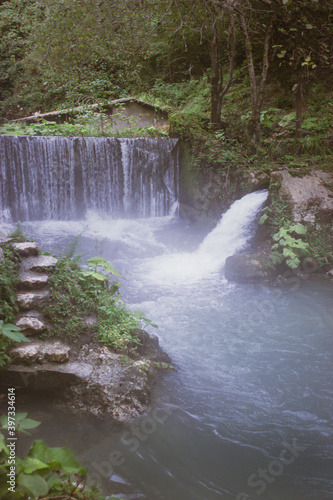 Beautiful nature, tourism, summer landscape, green grass and trees, river and mountains, waterfall