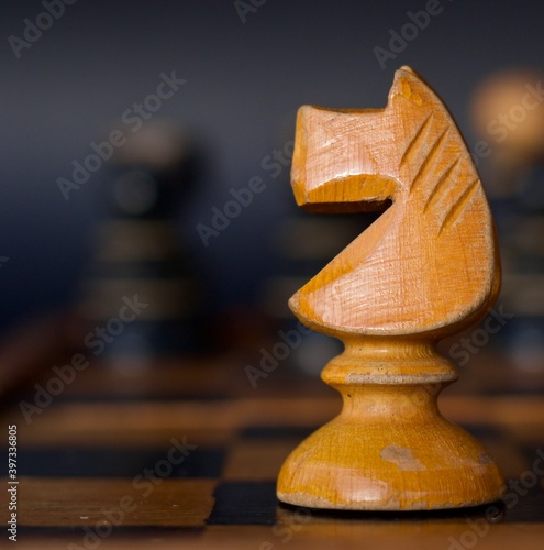 Knight Horse Wooden Chess Piece Handcrafted isolated on Chess Board, handmade, blurred background.