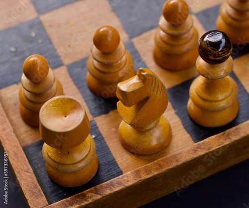 Vintage Wooden Chess Board with colored wooden black and natural wood figures. Pawns, queen, bishop, horse, the rook.