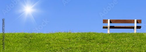 Photographie field with green grass and bench on sky background