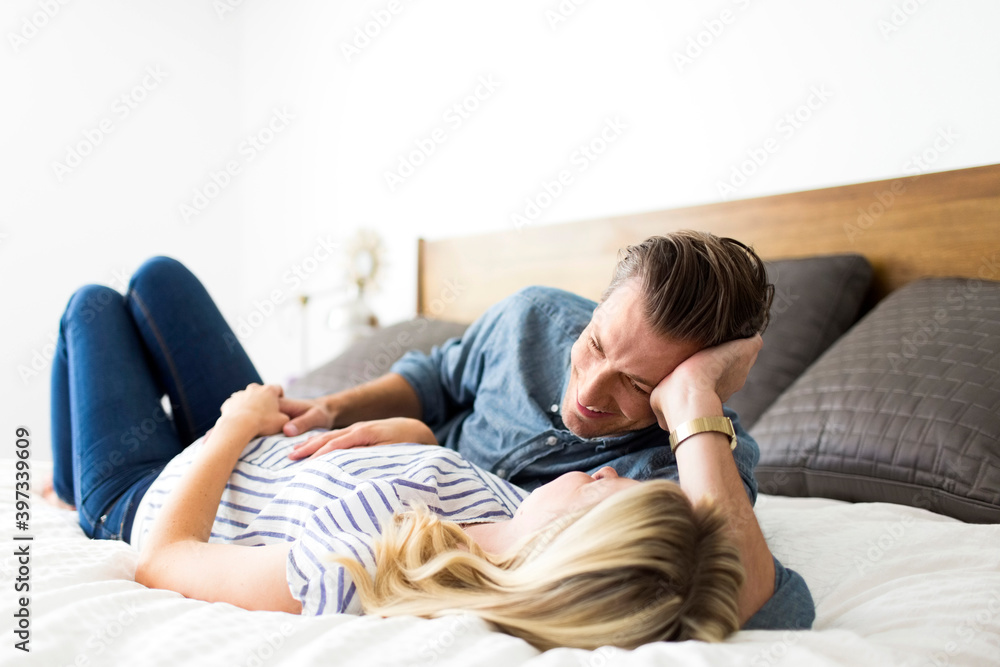 Husband lying down on bed with pregnant wife Husband lying down on bed with pregnant wife