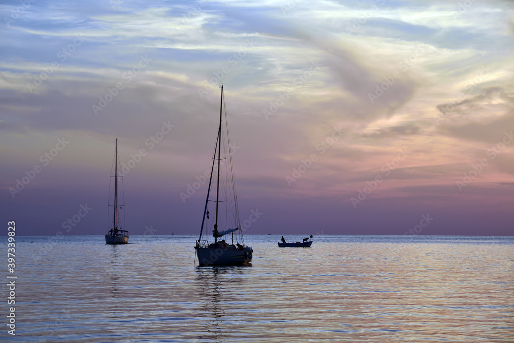 Sailboats anchored at sunset