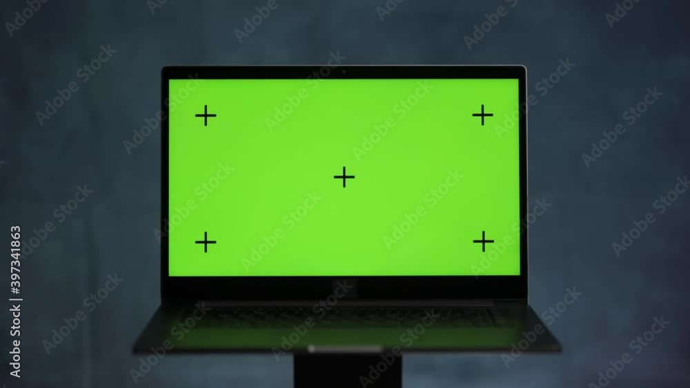 Laptop with a green screen and tracking points stands on a blue marble background and rotates Laptop with a green screen and tracking points stands on a blue marble background and rotates