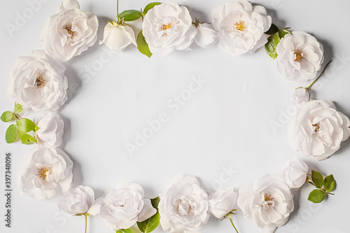 Floral frame wreath of white rose flower buds on white background. Flat lay, top view mockup. © Maryna