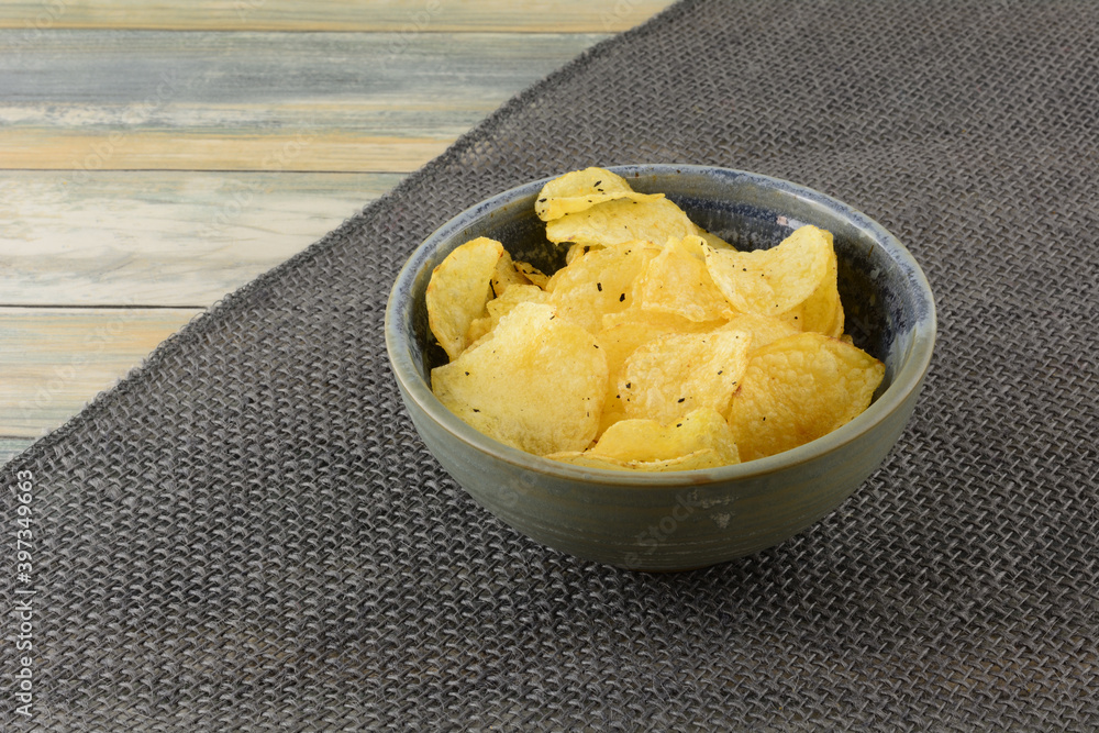 Italian black truffle potato chips in ceramic snack bowl on burlap table runner on table Italian black truffle potato chips in ceramic snack bowl on burlap table runner on table