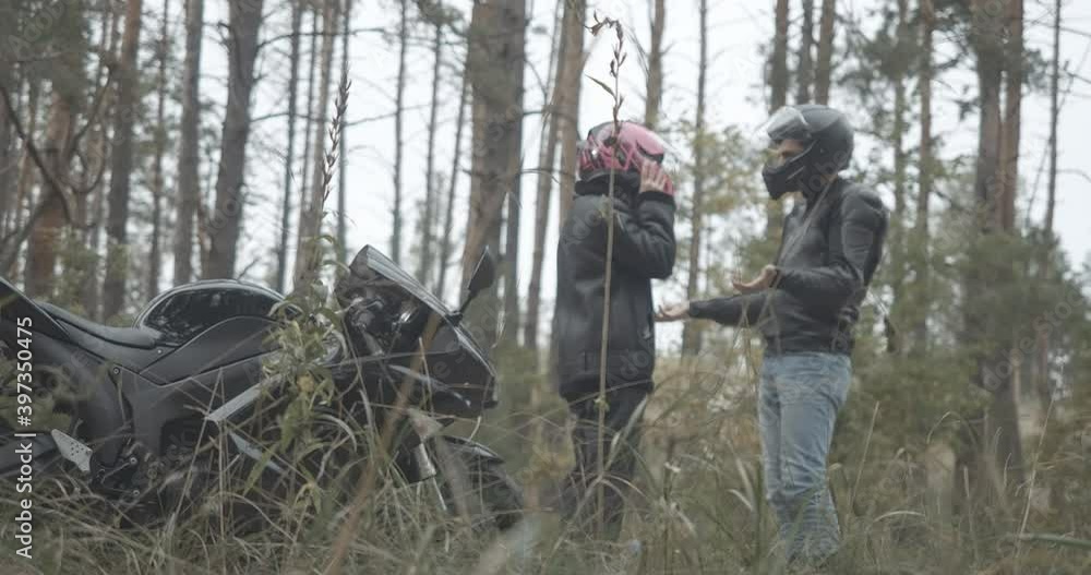 Wide shot of arguing couple of young motorbikers on empty roadside. Angry stressed man and woman yelling and gesturing outdoors on cloudy spring or autumn day. Cinema 4k ProRes HQ. Wide shot of arguing couple of young motorbikers on empty roadside. Angry stressed man and woman yelling and gesturing outdoors on cloudy spring or autumn day. Cinema 4k ProRes HQ.