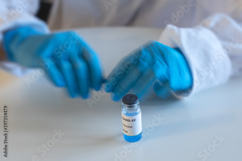 Concept of Covid 19 vaccine vaccinating, development and creation, doctor or scientist in laboratory holding a single dose of  2019-ncov vaccine, a syringe and ampule with SARS-CoV-2 vaccination