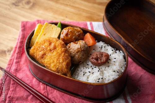 Fotografie japanese style bento in wooden box with meat ball and croquette