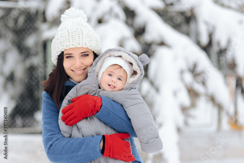 Happy Mother Holding Baby Enjoying Snow in Wintertime