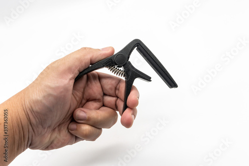 Hand holding the matte black capo for acoustic and classical guitar isolated on white photo