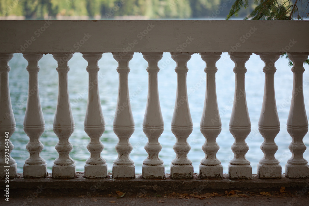 Fototapeta premium White stone railings with balustrades, in the background of the pond