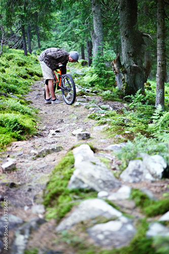 Young caucasian cyclist repairs a mountain bike in the mountains in the forest.