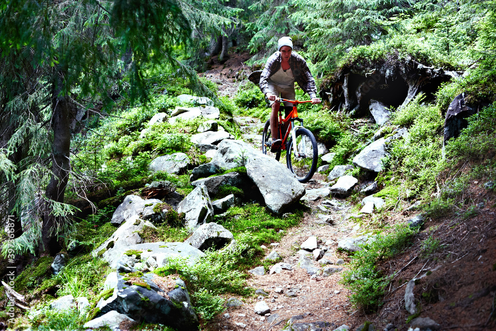 Young caucasian cyclist on a mountain bike rides along mountain trails in a mountain forest. Young caucasian cyclist on a mountain bike rides along mountain trails in a mountain forest.