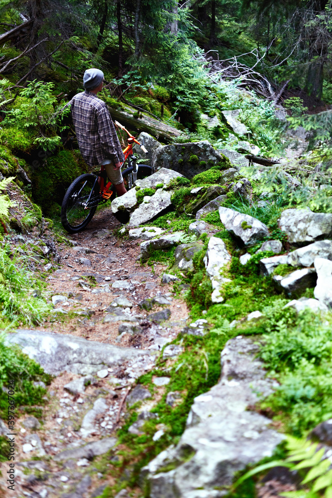 Young caucasian cyclist on a mountain bike rides along mountain trails in a mountain forest. Young caucasian cyclist on a mountain bike rides along mountain trails in a mountain forest.