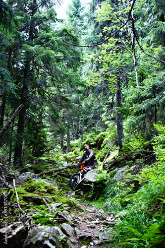 Young caucasian cyclist on a mountain bike rides along mountain trails in a mountain forest.