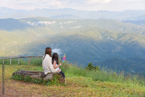 Mother and daughter sit and watch the beautiful mountain view Look at the vast nature
