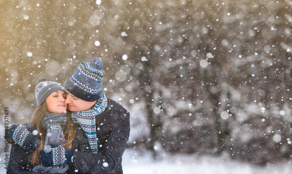 Loving couple in wool hats embracing in the winter forest Loving couple in wool hats embracing in the winter forest