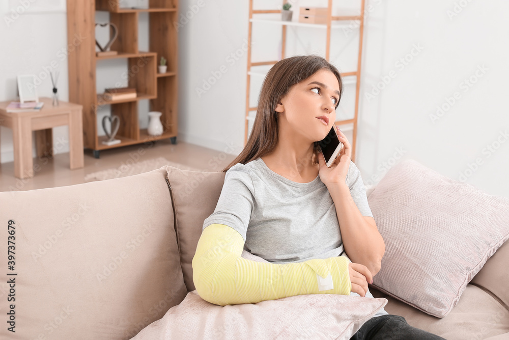 Young woman with broken arm talking by phone at home Young woman with broken arm talking by phone at home