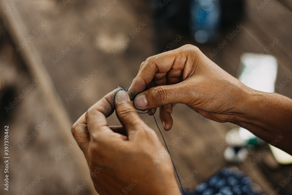 Thread into the needle. Close-up of woman's hand pulling thread into the needle. folk art, sensuous silk Thread into the needle. Close-up of woman's hand pulling thread into the needle. folk art, sensuous silk