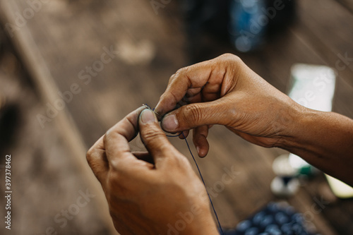 Thread into the needle. Close-up of woman's hand pulling thread into the needle. folk art, sensuous silk
