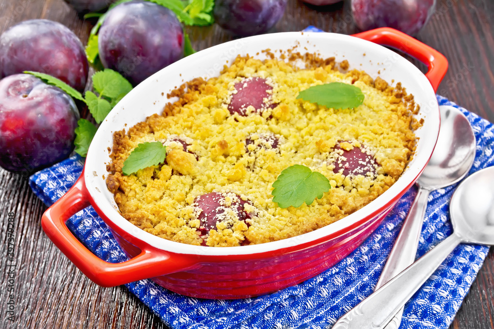 Crumble with plum in brazier on dark board Crumble with plum in brazier on dark board