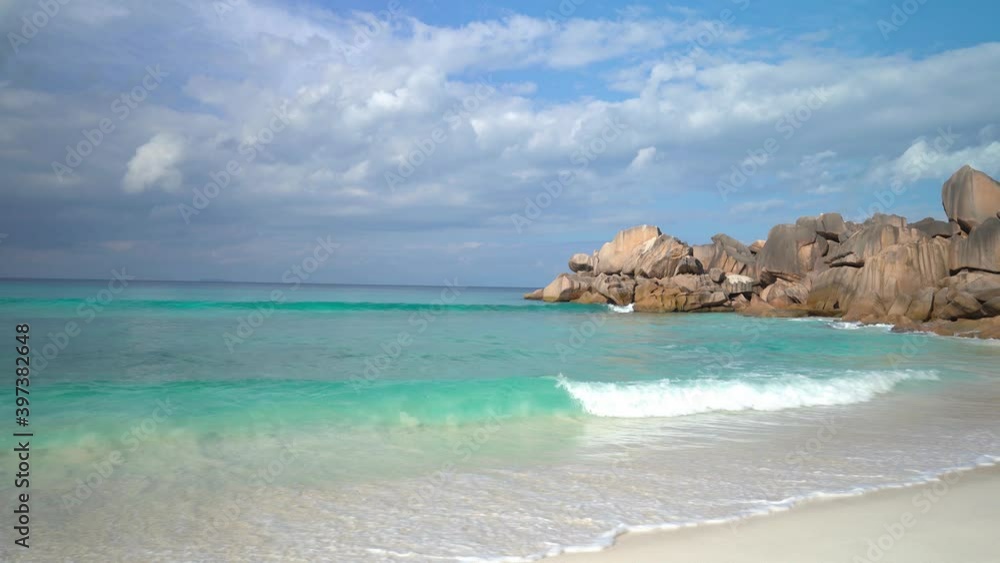 Exotic beach by the ocean with rolling waves on the sandy shore and blue sky Exotic beach by the ocean with rolling waves on the sandy shore and blue sky