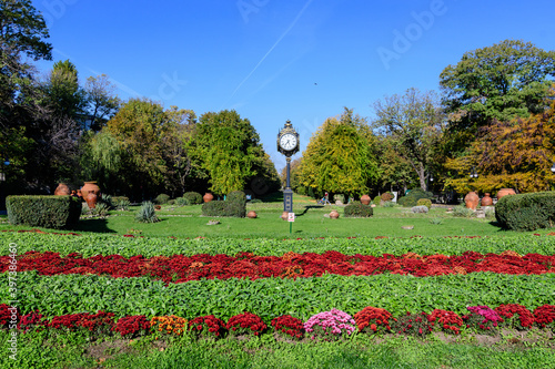 Landscape with the main entrance with vivid green and yellow plants, green lime trees and grass in a sunny autumn day in Cismigiu Garden in Bucharest, Romania .