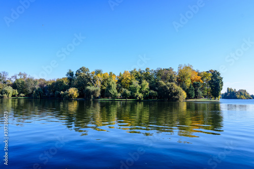 Landscape with many large green trees near the lake in Herastrau Park in Bucharest  Romania   in a sunny autumn day.