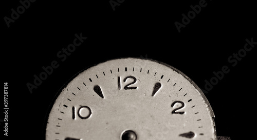 Vintage wall clock on a dark background. Selective focus. Vintage light toning. Grunge style backdrop