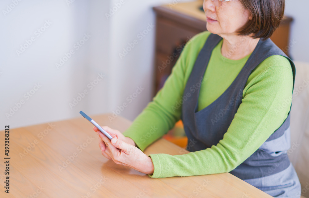 Japanese senior woman use smart phone in living room Japanese senior woman use smart phone in living room
