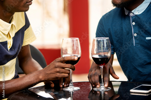 two young people each holding a glass of red wine
