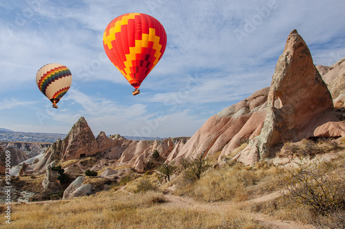 Bright balloons hover over a valley in Cappadocia. Turkey