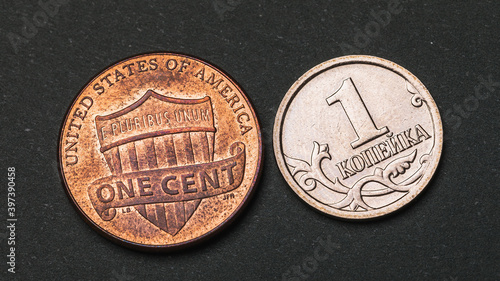 One Russian kopeck and an American cent on a dark background