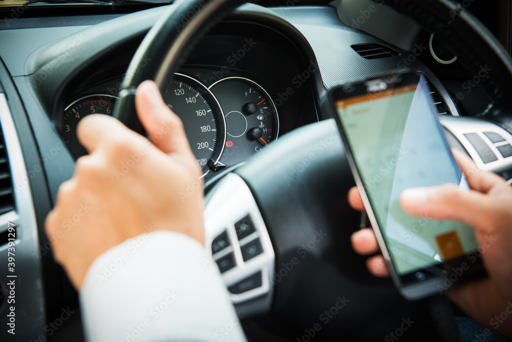 A man sitting in car using smart phone, business man busy driving,uses the navigation in the smartphone