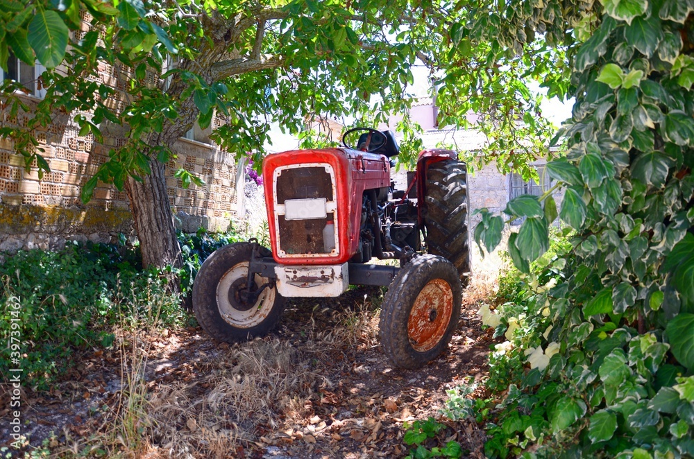 An old tractor surrounded by greenery in a remote village on the island of Zakynthos, Greece An old tractor surrounded by greenery in a remote village on the island of Zakynthos, Greece