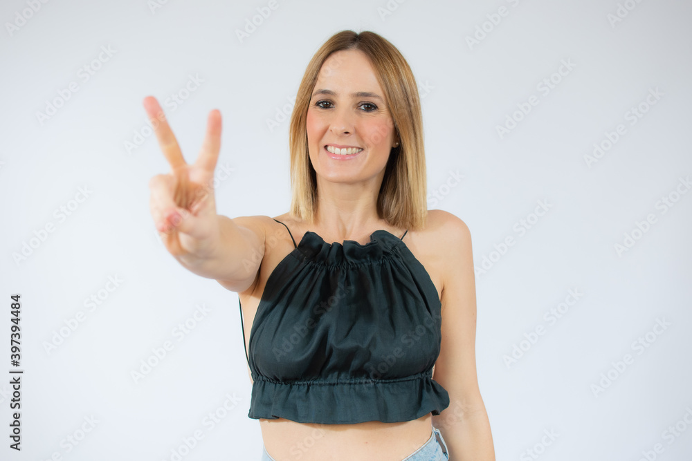 Blonde woman over isolated background smiling and showing victory sign Blonde woman over isolated background smiling and showing victory sign