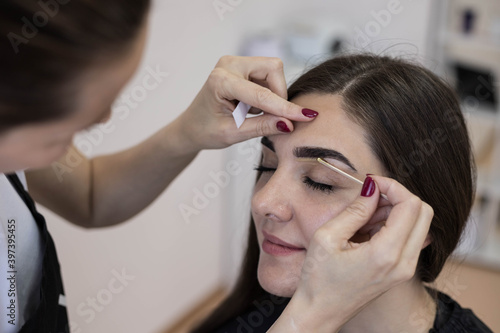 The master applies wax to depilate the hair of the eyebrows. Eyebrow correction.Wax epilation spa procedure. 