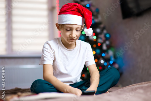 a child in a Christmas Santa hat on the background of a garland