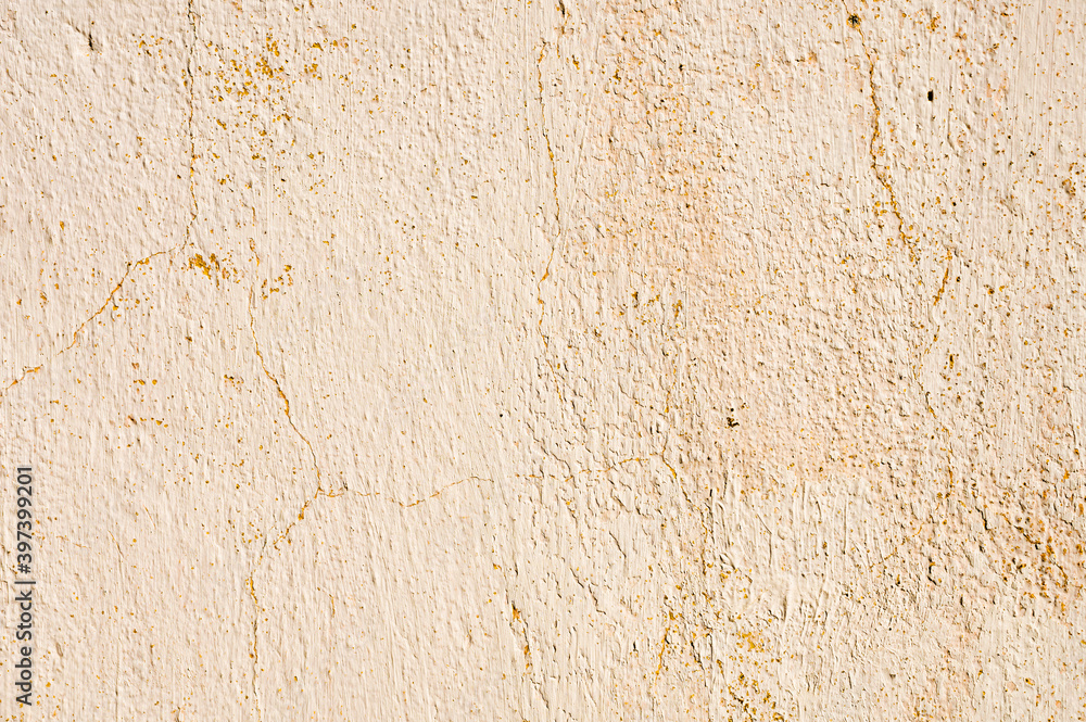 Grunge background of cracked peeling walls with peeled putty in beige tones
