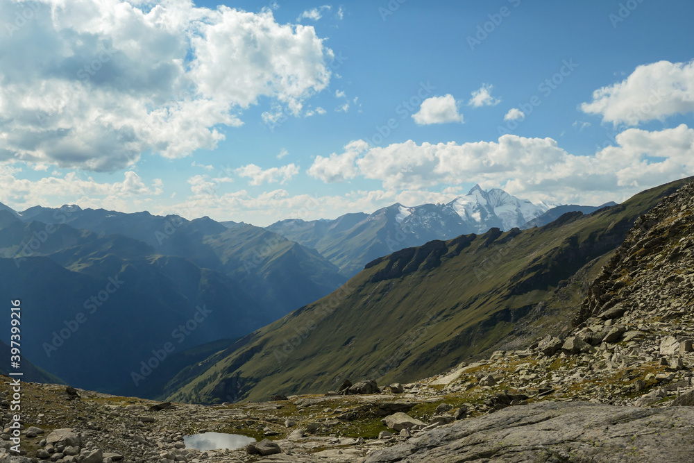 Obraz premium Panoramic view from Hohe Sonnblick in Austrian Alps on Gro?glockner. The whole area is very steep and dangerous, with many lose stones. Green, steep meadows in front. Sunny day. Expedition
