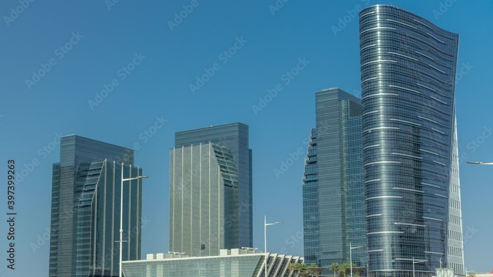Modern buildings of Al Maryah Island in Abu Dhabi skyline timelapse with traffic on the road. View from the bridge with reflections on skyscrapers Modern buildings of Al Maryah Island in Abu Dhabi skyline timelapse with traffic on the road. View from the bridge with reflections on skyscrapers
