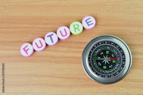 Top view of compass and alphabet erasers with text FUTURE over wooden background. Business and education concept.