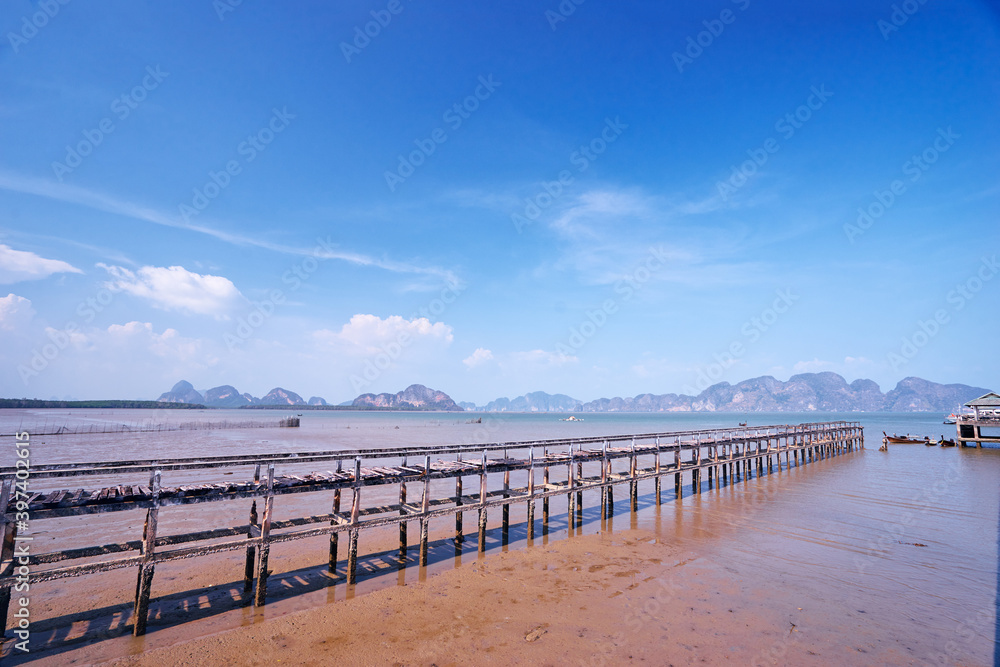 Beautiful old pier on the sea shore. Traveling by Thailand. Landscape with sea lagoon, pier and traditional fishing longtail boats.