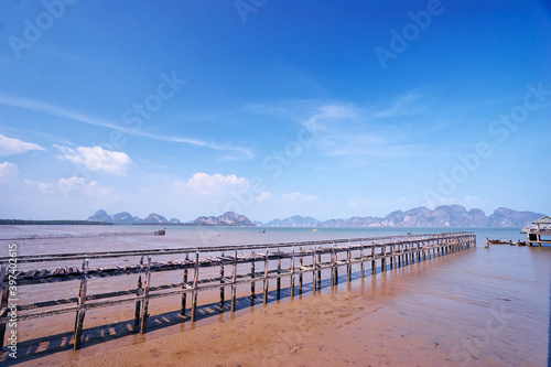 Beautiful old pier on the sea shore. Traveling by Thailand. Landscape with sea lagoon, pier and traditional fishing longtail boats. © luengo_ua