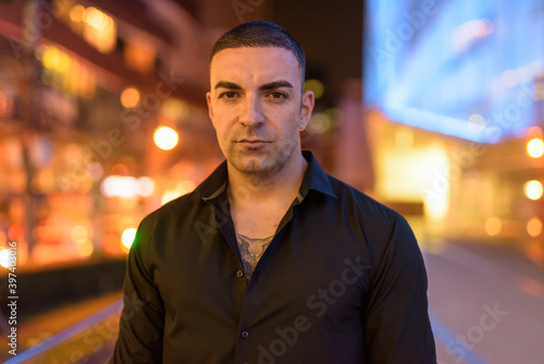 Portrait of handsome man with short hair outdoors at night in city