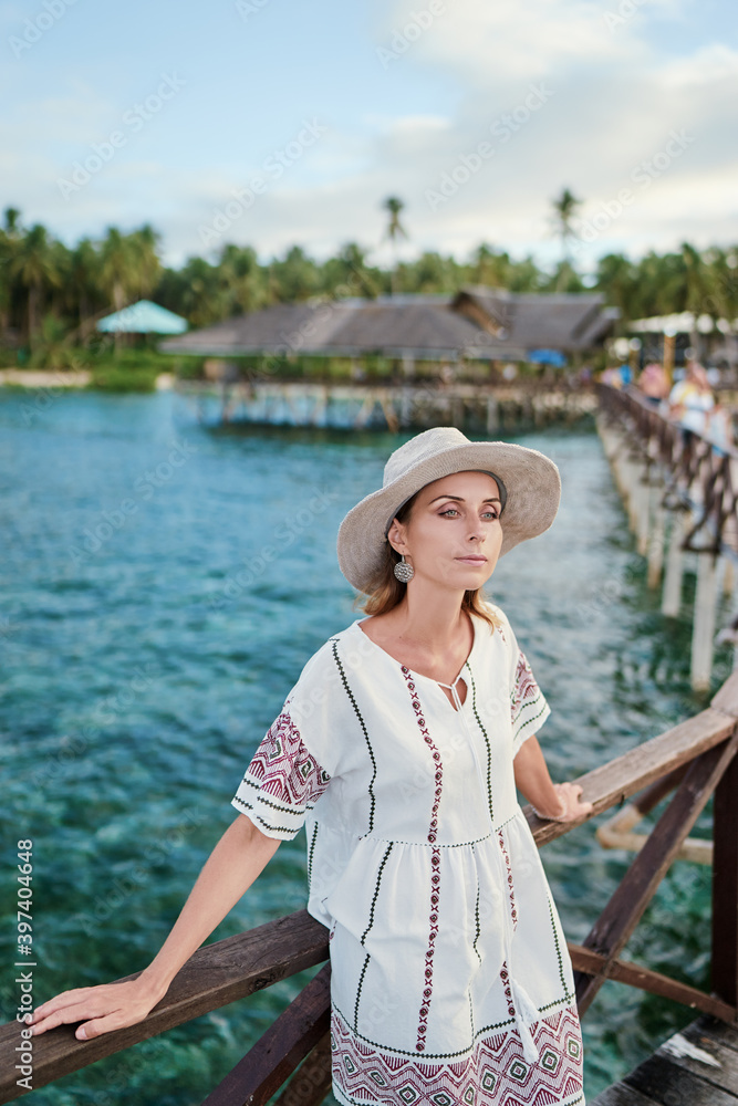 Vacation on tropical island. Young woman in hat enjoying sea view from wooden bridge terrace, Siargao Philippines.