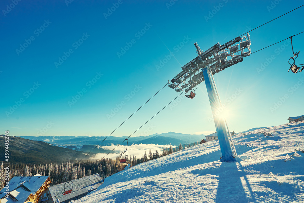 Ski lift with seats going over the mountain and paths from skies and snowboards. Beautiful winter landscape. Ski lift with seats going over the mountain and paths from skies and snowboards. Beautiful winter landscape.